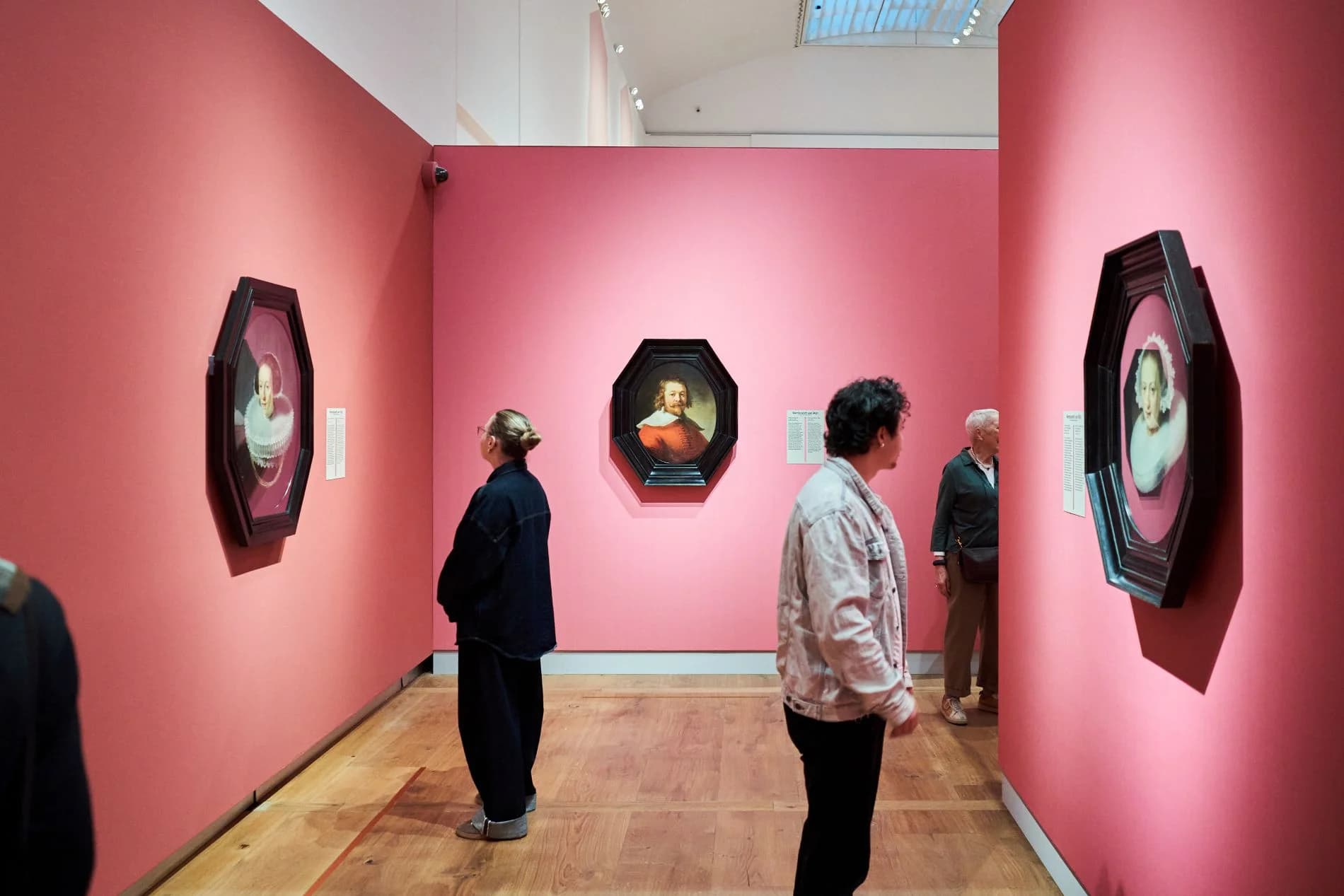 Exhibition view at the H'ART Museum with visitors before Leiden Collection portraits in octagonal frames