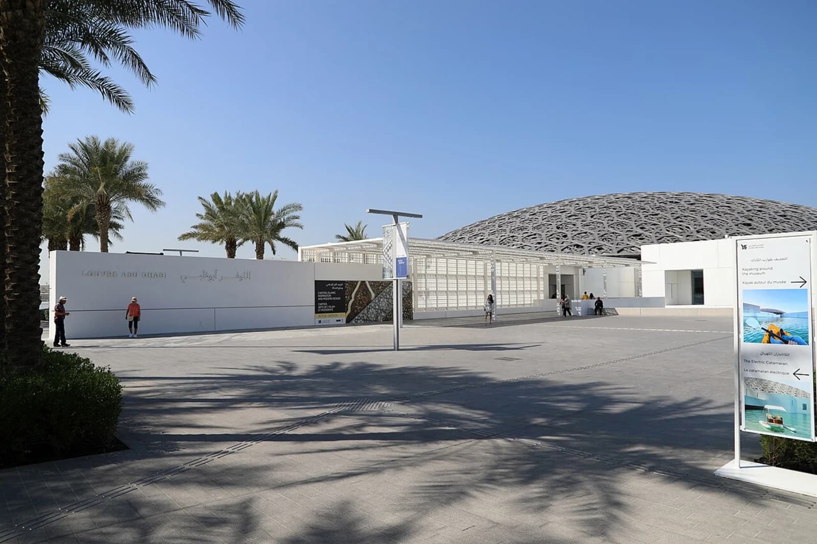 Exterior view of the Louvre Abu Dhabi, showing the distinctive perforated dome designed by Jean Nouvel over the low white pavilions on the waterfront