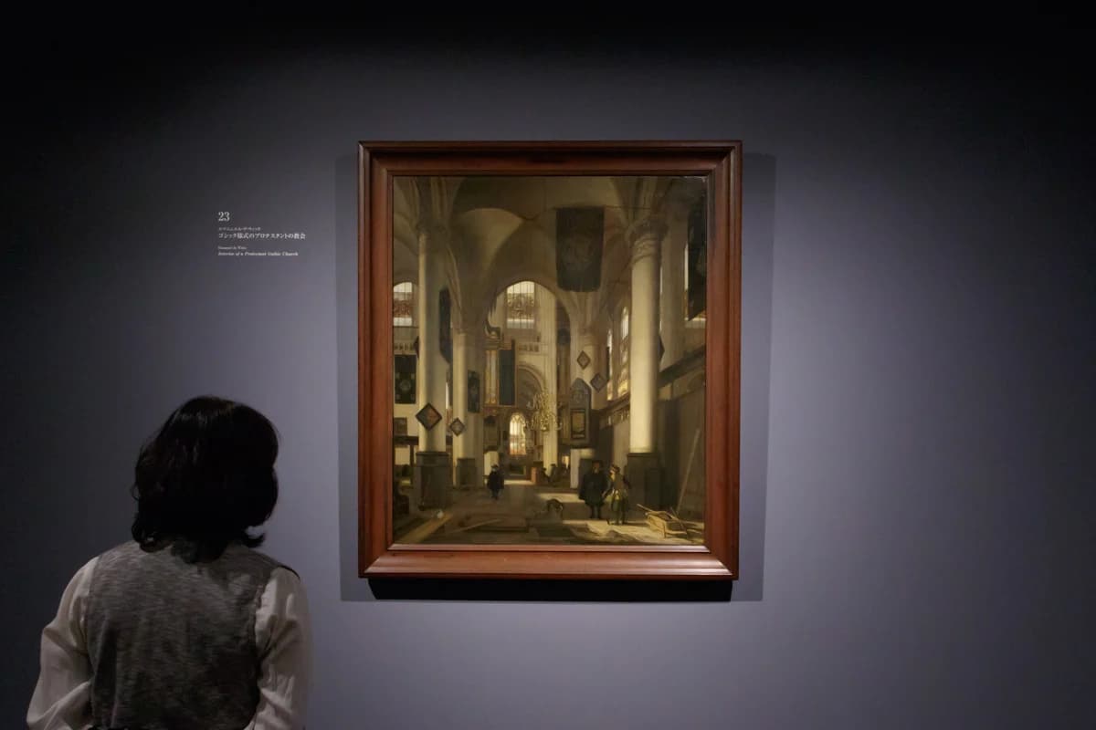 A single visitor viewing Emanuel de Witte's Interior of a Protestant Gothic Church in a dim gallery