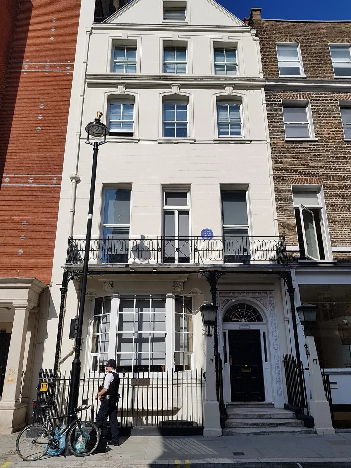 The Georgian townhouse at 17 Savile Row in London, former premises of the Burlington Fine Arts Club, a four-storey red brick building with white stone trim, sash windows, iron balconies and railings, and a blue plaque commemorating architect George Basevi.