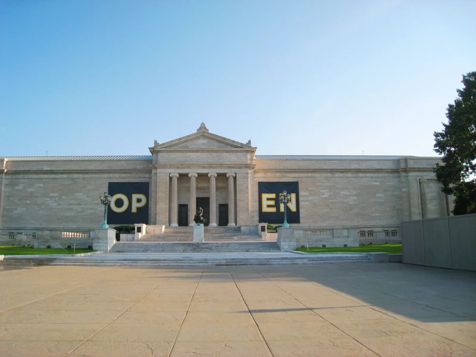 The Beaux-Arts south facade of the original 1916 building of the Cleveland Museum of Art, featuring classical columns, pediment, and entrance portico set in Wade Park with trees and lawn under a blue sky.