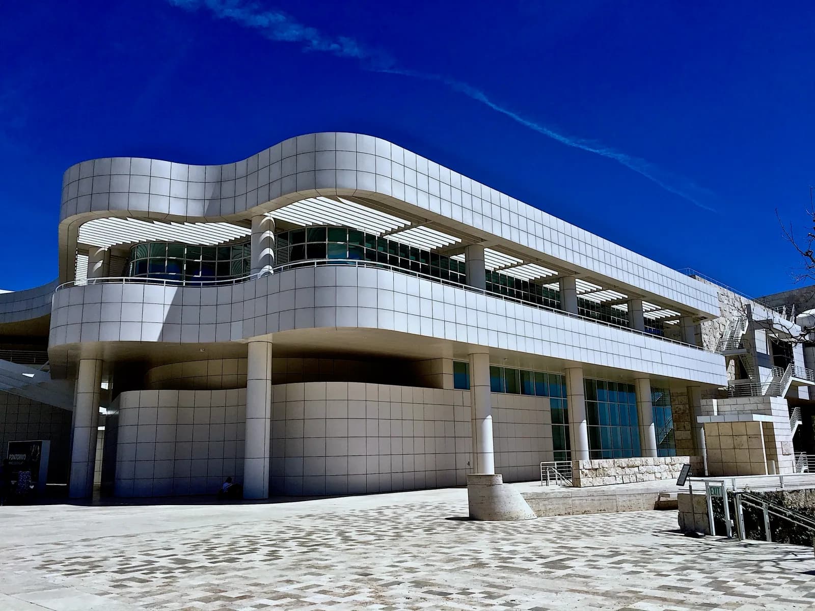 The Richard Meier-designed Getty Center in Los Angeles, featuring its distinctive white travertine buildings, geometric architecture, and central garden with a tram under a clear sky.