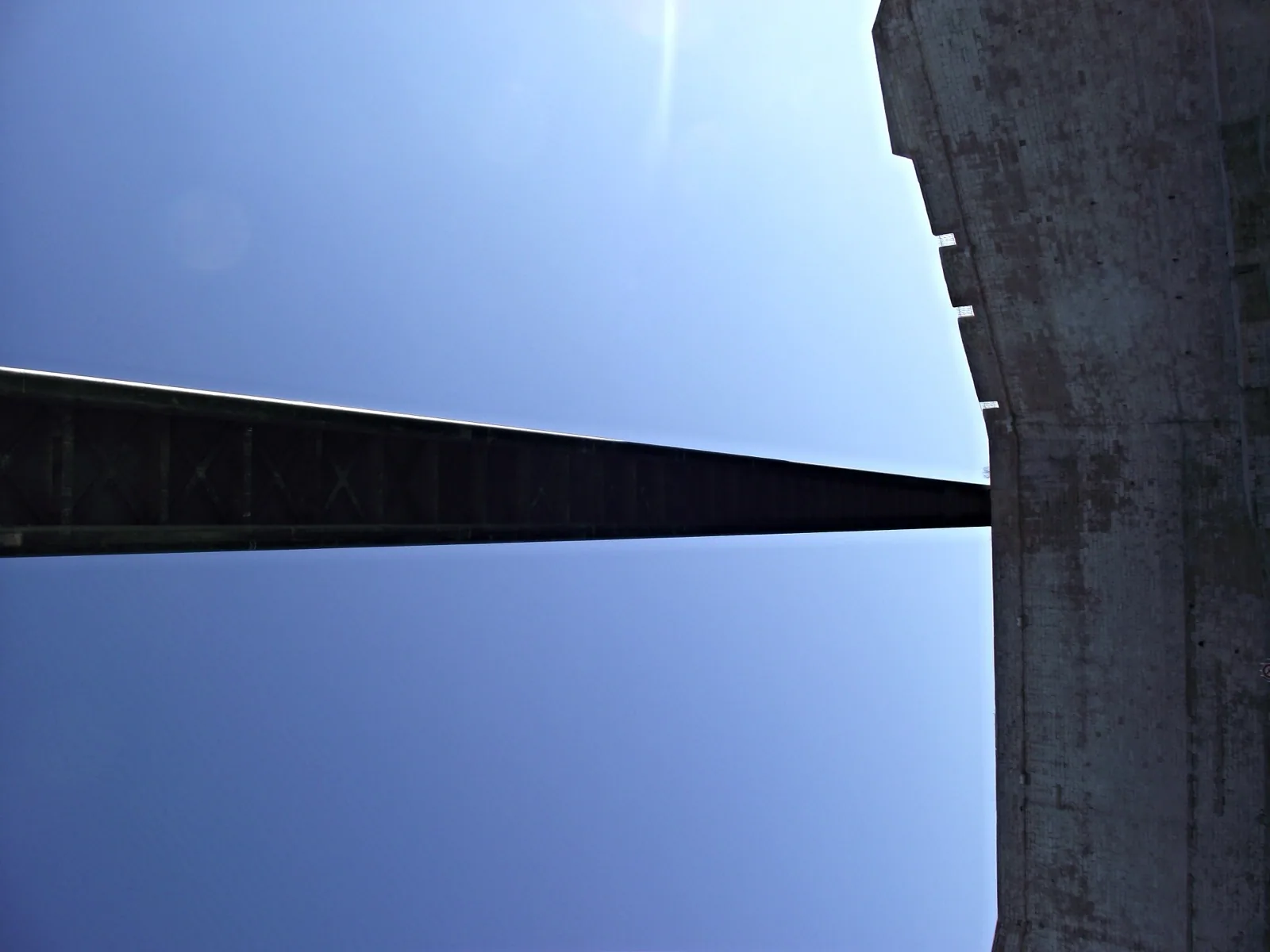 The dramatic cantilevered concrete facade of the Mucem (Musée des Civilisations de l'Europe et de la Méditerranée) in Marseille, with its distinctive lattice design and connection to Fort Saint-Jean, viewed from below against a clear blue sky.
