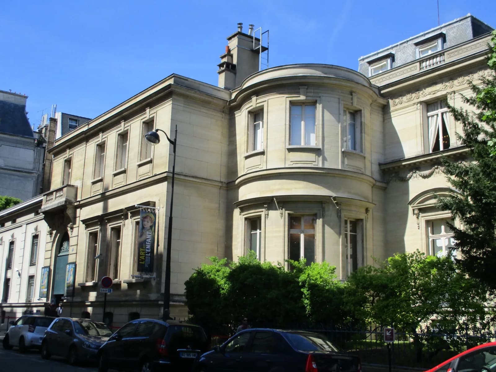 The elegant 19th-century stone facade of the Musée Marmottan Monet in Paris, a former hunting lodge turned museum with symmetrical windows, balconies, and entrance portico, surrounded by trees in the 16th arrondissement.
