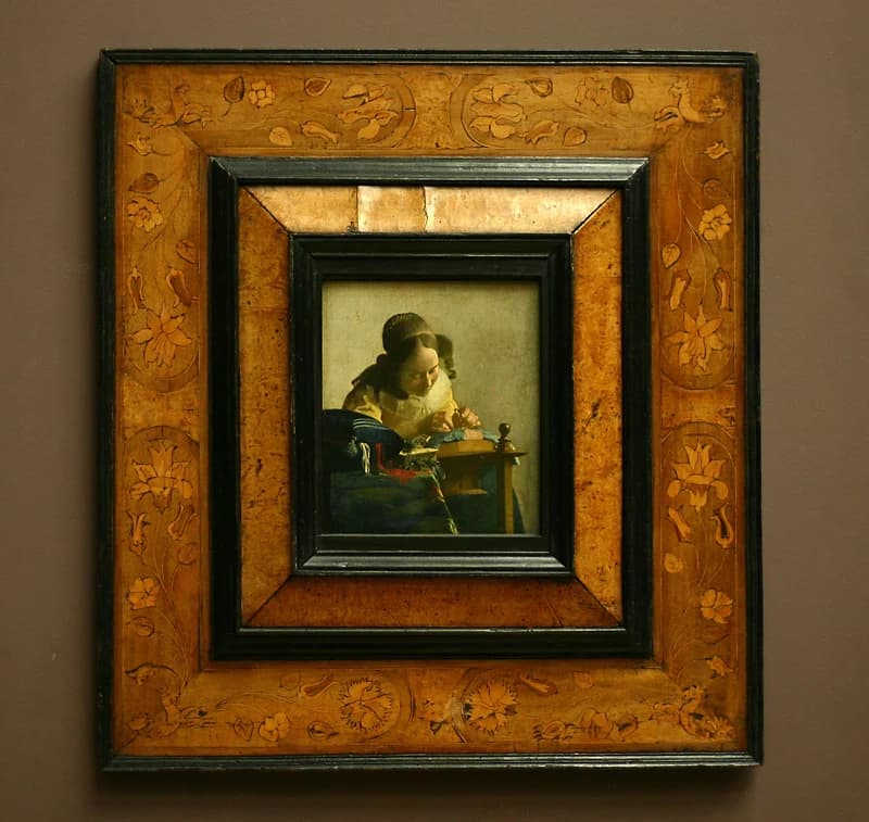 The Lacemaker in its ornate marquetry frame at the Louvre, Paris