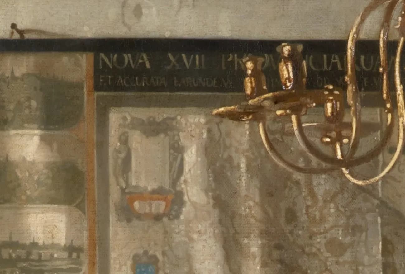 Detail of the top of the wall map, its roller and finial knobs and the Latin title band, with an arm of the chandelier in front