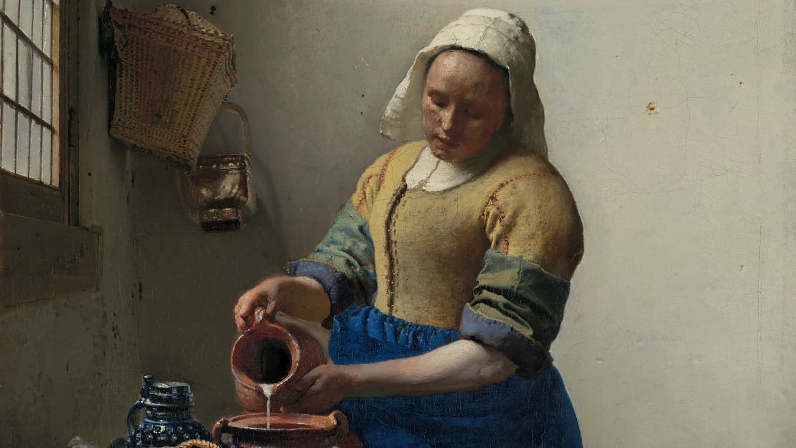 Vermeer's Milkmaid pouring milk into a bowl, a wicker basket on the bare wall behind her