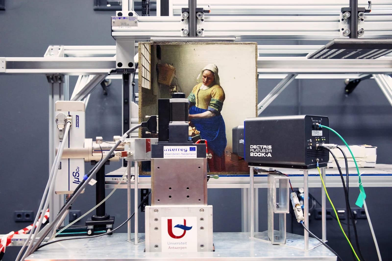 The Milkmaid mounted upright on a macro-XRF scanning rig in a laboratory, surrounded by detector and electronics