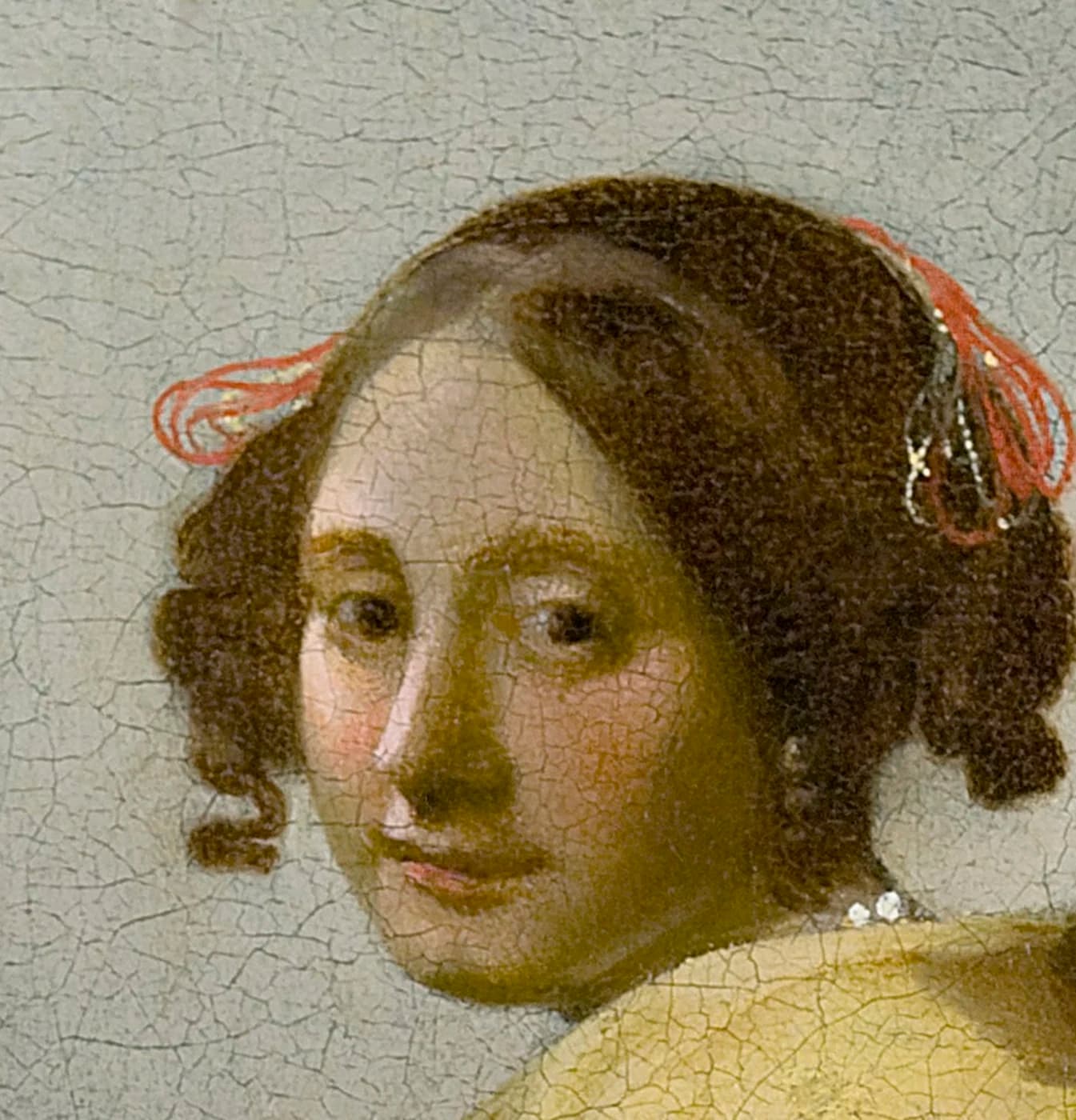 Detail of the woman's face, her eyes meeting the viewer, with coral ribbons in her hair and a pearl at her ear