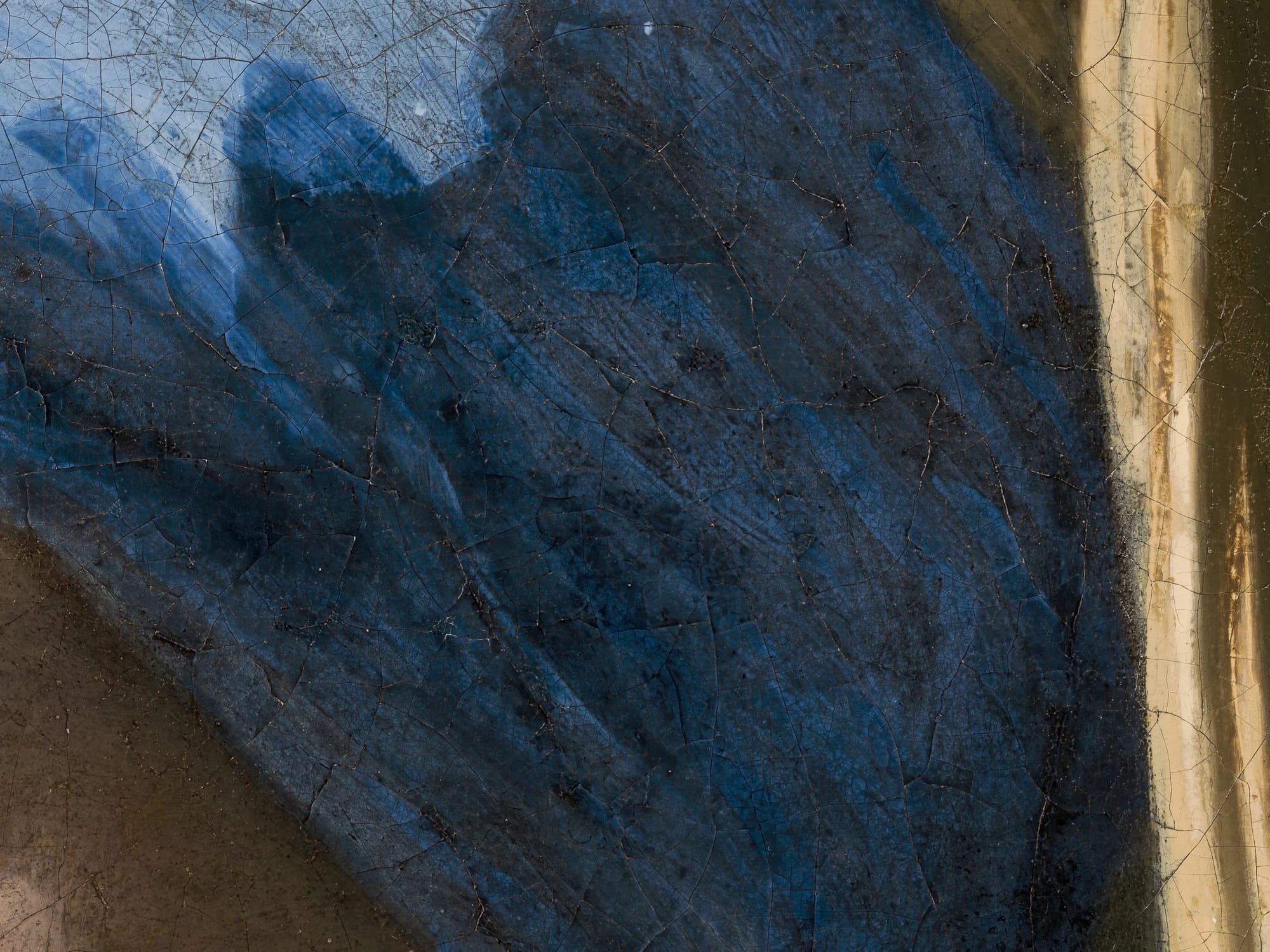 Magnified detail of the shadow side of the blue headscarf in Girl with a Pearl Earring, the dark blue paint mottled and patchy from degradation